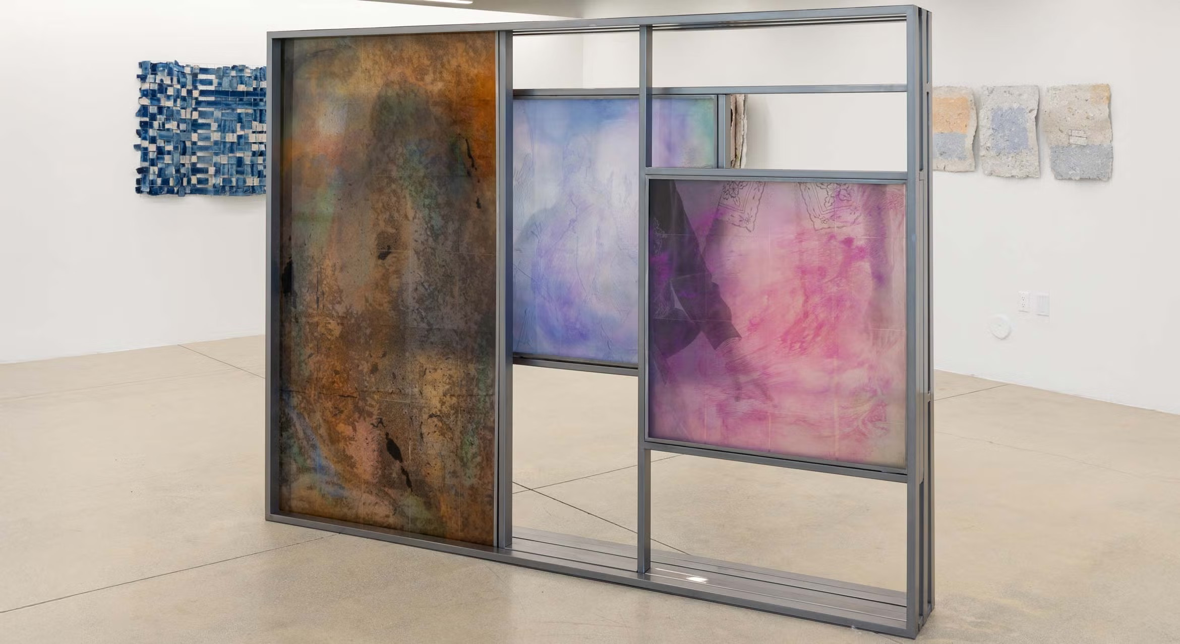 Artist Kim Garcia's installation, "What you can never fully hold," featuring layered, translucent resin panels in a steel frame, on display in a gallery.